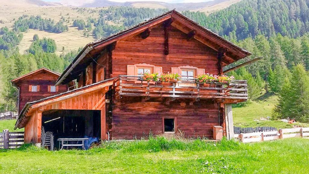 Una antigua cabaña de troncos con flores en el balcón. en Almhütte Haritzer, en Schachnern