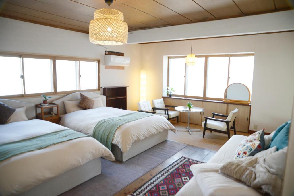 ein Schlafzimmer mit zwei Betten und ein Wohnzimmer in der Unterkunft 宇都宮ゲストハウス花ニ嵐 in Utsunomiya