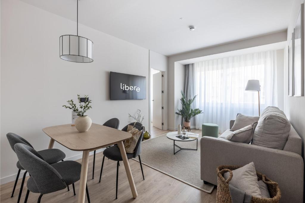 Una sala de estar con un sofá, una mesa y sillas. en Líbere Madrid Chamberí, en Madrid
