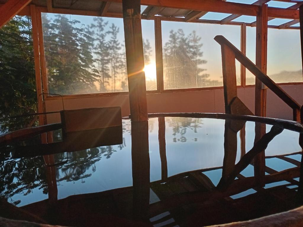 a reflection of a table and chair in a pool at Cabañas Tinaja y Sauna Laguna Verde Valparaiso in Valparaíso