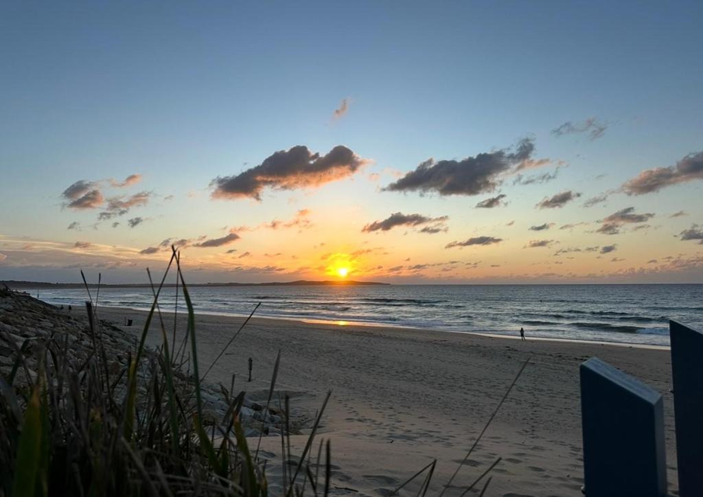 einen Sonnenuntergang am Strand mit dem Meer in der Unterkunft Plumeria Cottage Haven by the Beach 25mins from Sydney CBD in Rock Islet