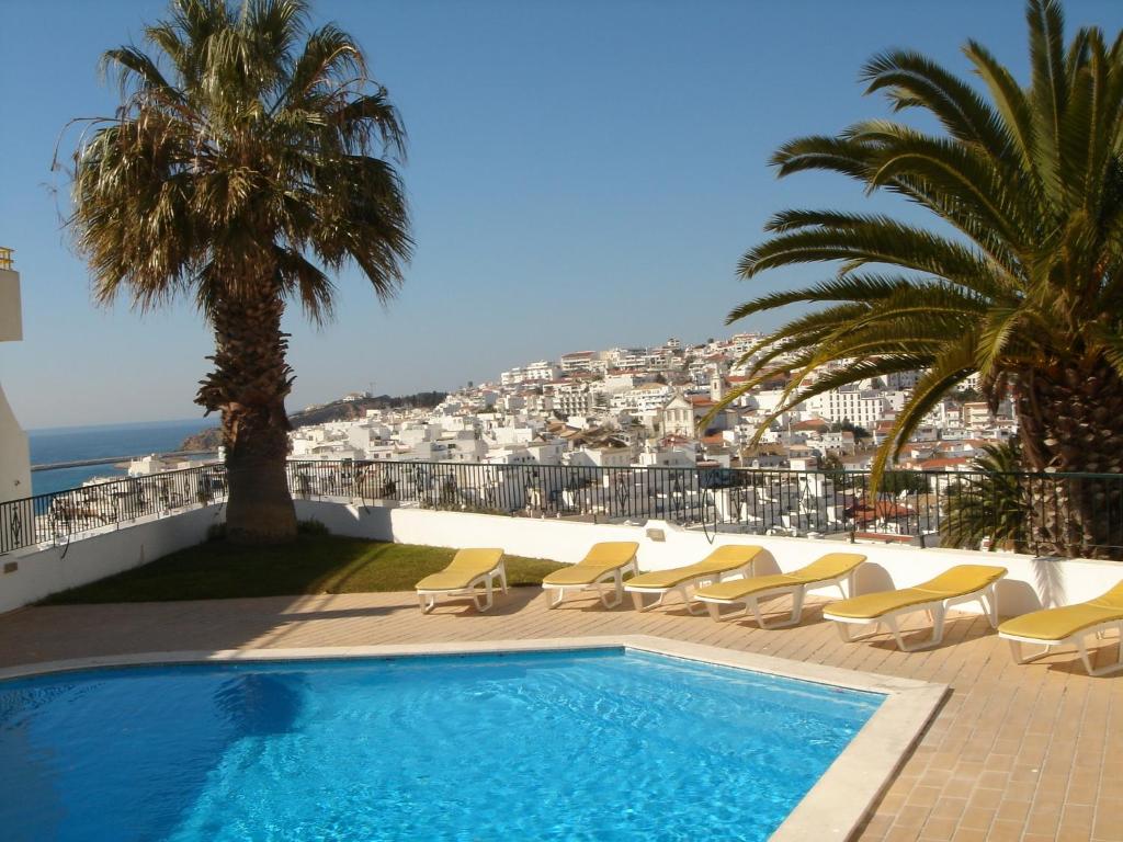 a swimming pool with chairs and a view of the ocean at SILMAR by Cerro Mar in Albufeira