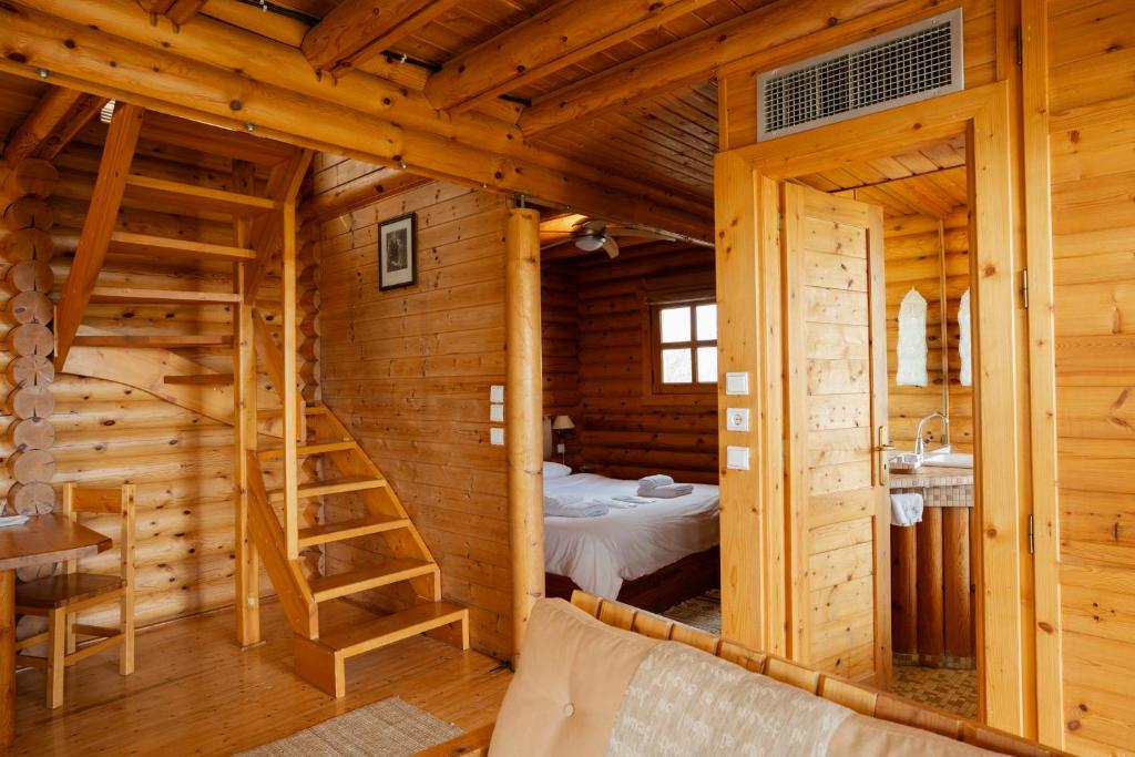 una cabaña de troncos con una cama y una escalera en Hyades Mountain Resort, en Kato Trikala Korinthias