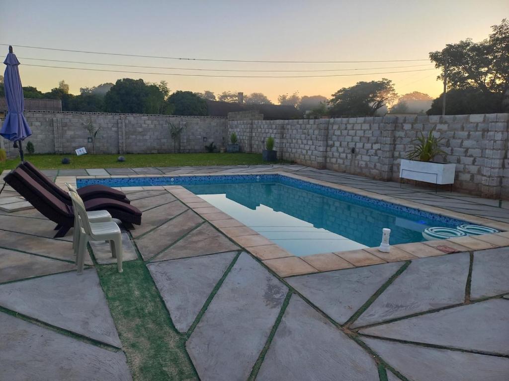 uma piscina com uma cadeira ao lado de uma parede em Yeta Apartments em Livingstone