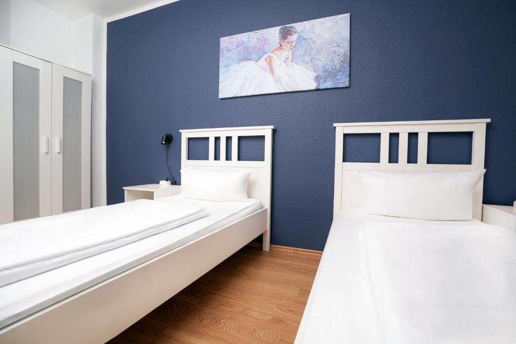 two beds in a room with a blue wall at Shin West in Essen