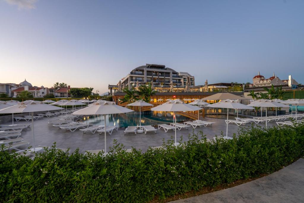 a group of umbrellas and chairs and a pool at Sentido Luna Vista Belek Hotel in Belek