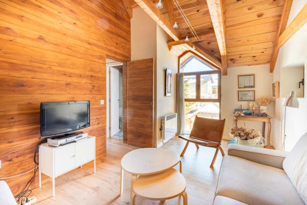 uma sala de estar com paredes de madeira e uma televisão em El Pajar de la Leña - tucasaenlospirineos em Sandiniés