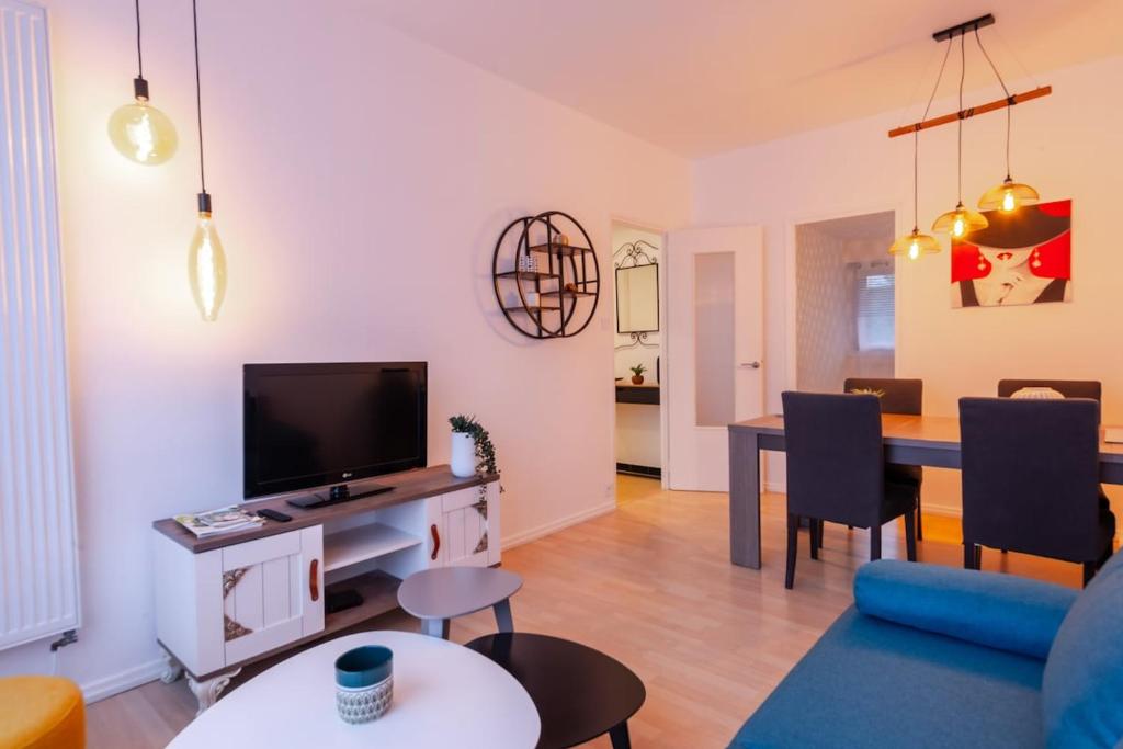 a living room with a television and a dining room at Le Bleu des Remparts in Chalon-sur-Saône
