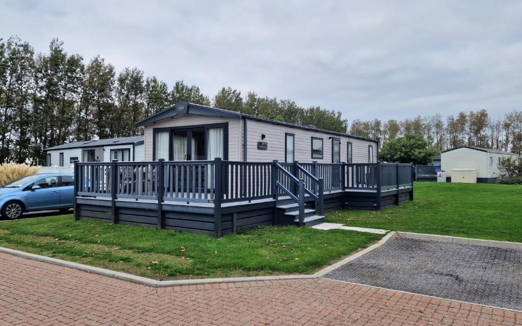 a tiny house with a porch and a car at The Good Life, The Boulevard, Selsey in Selsey