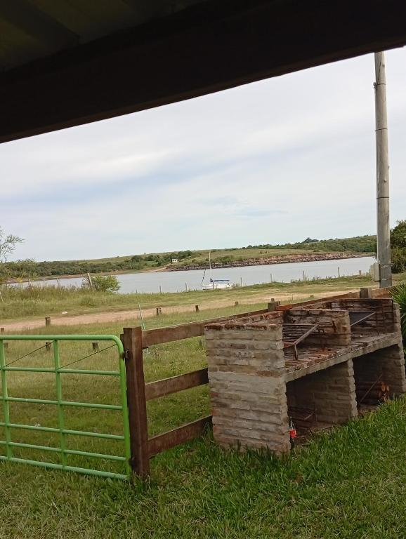 a stack of logs next to a fence and a body of water at Apartamento La Balsa in San Gregorio de Polanco