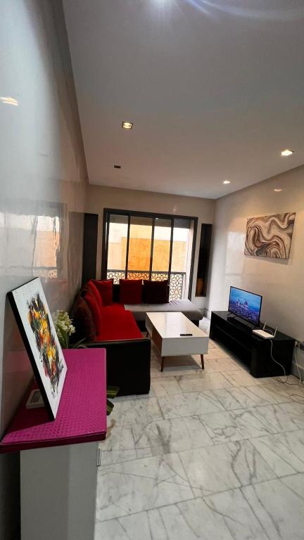 a living room with a red couch and a tv at Beautiful appartement with pool view in Mohammedia