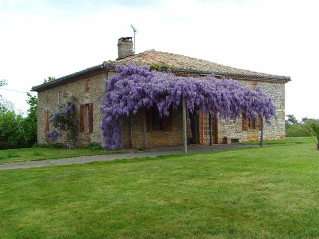 a house with a wreath of purple flowers on it at La Plaine in Puygaillard-de-Quercy