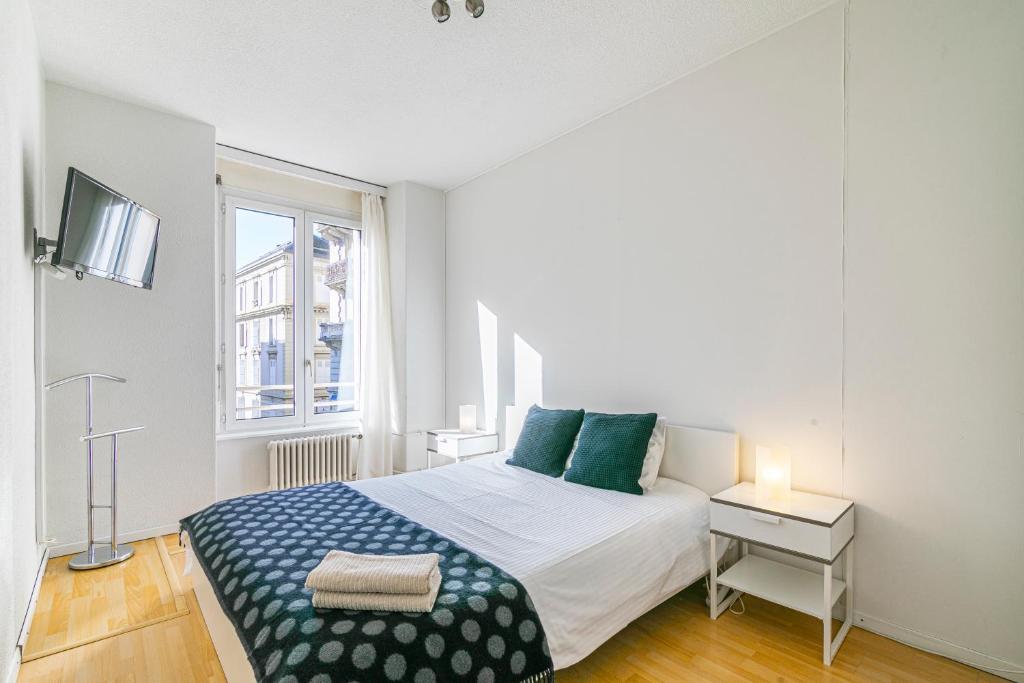ein weißes Schlafzimmer mit einem Bett und einem Fenster in der Unterkunft Simplon Residence - Central and Self Check In in Lausanne