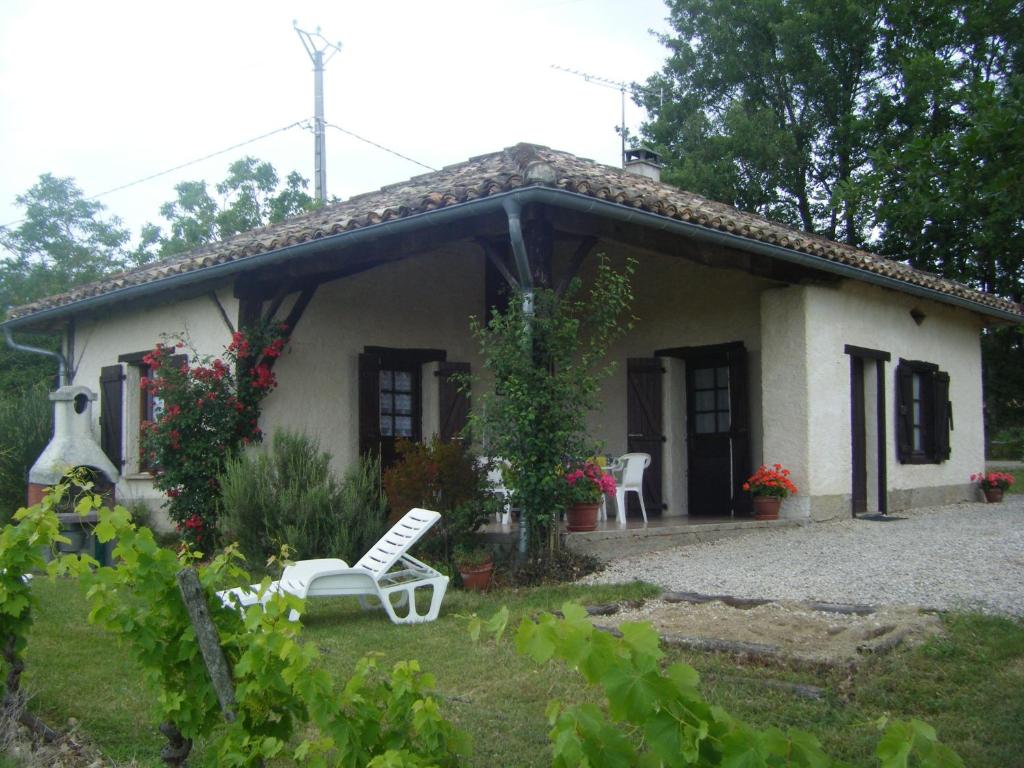 une maison avec une chaise blanche devant elle dans l'établissement Gîte de Raoussou, à Mirabel