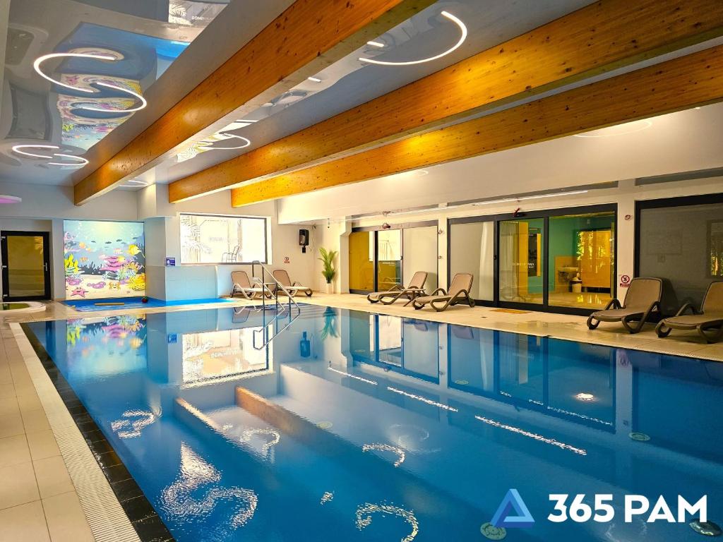 une grande piscine avec des chaises dans un bâtiment dans l'établissement 365PAM - Studio Białe i Czarne w Dominikanie Przy Morzu, à Sianożęty