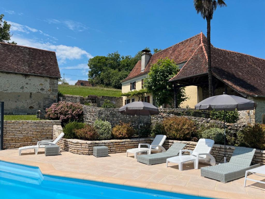 ein Pool mit Stühlen und Sonnenschirmen neben einem Haus in der Unterkunft Domaine Cherps Spa - Quietude in Vielleségure