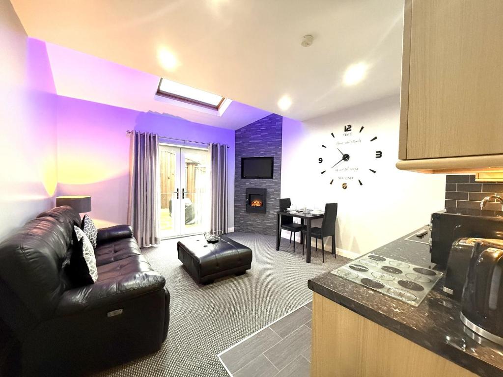 a living room with a couch and a clock on the wall at Maggie's Lodge in Leeds