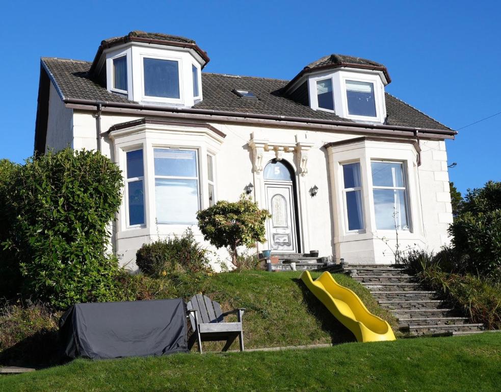 a white house with a yellow slide in front of it at Carmona Bank in Dunoon