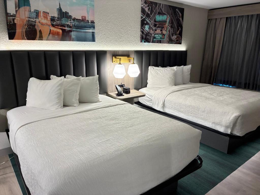 una camera d'albergo con due letti con lenzuola bianche di La Quinta by Wyndham Nashville Airport/Opryland a Nashville