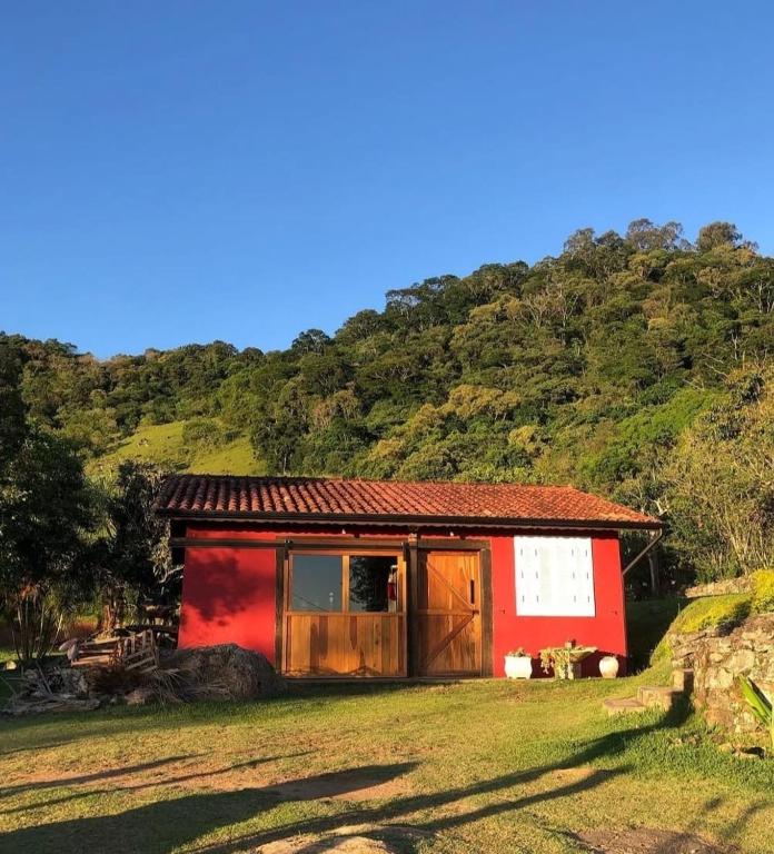a small red building with a mountain in the background at Chalé Joanópolis - Rancho da Biruta in Joanópolis