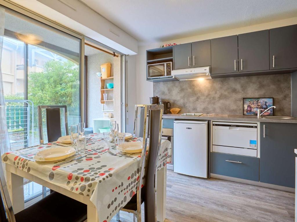 a kitchen with a table with a table cloth on it at T2 cosy, jardinet, animaux admis, parking et WiFi - FR-1-841-35 in Barbotan-les-Thermes