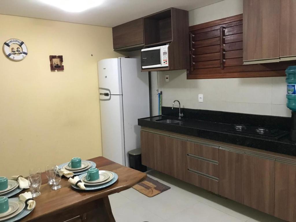 a kitchen with a table and a white refrigerator at AP 104 - Flecheiras Residence in Flecheiras