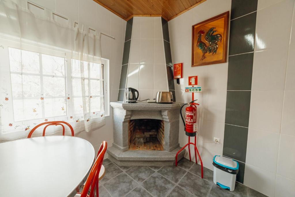 une cuisine avec une cheminée, une table et des chaises dans l'établissement Casa do Malhadinhas - Vacationy, à Vila Nova de Paiva