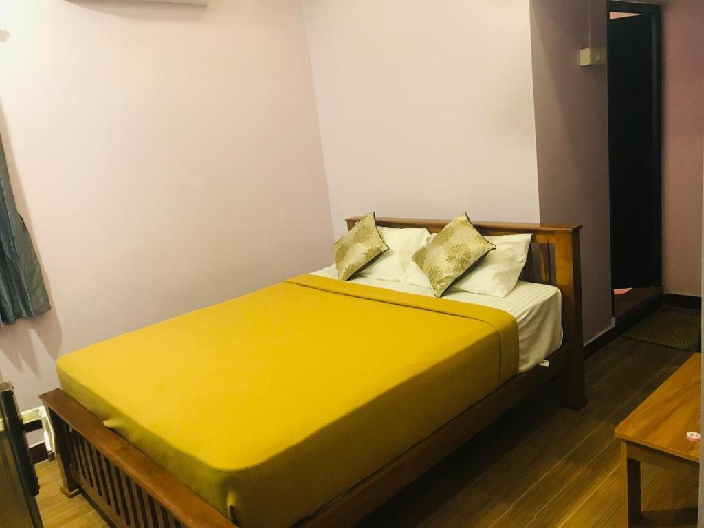 a bed with yellow sheets and pillows in a room at Padma residency in Coimbatore