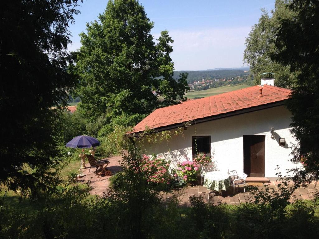 une maison blanche avec un toit rouge et un parapluie dans l'établissement Ferienhaus Mit Einer Umwerfenden Panoramaaussicht, à Glotzdorf