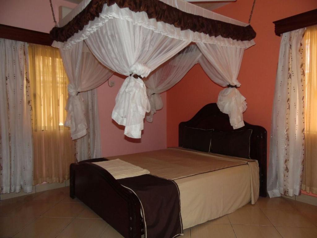 a bedroom with a bed with a canopy and curtains at Barizi Cottage in Mombasa