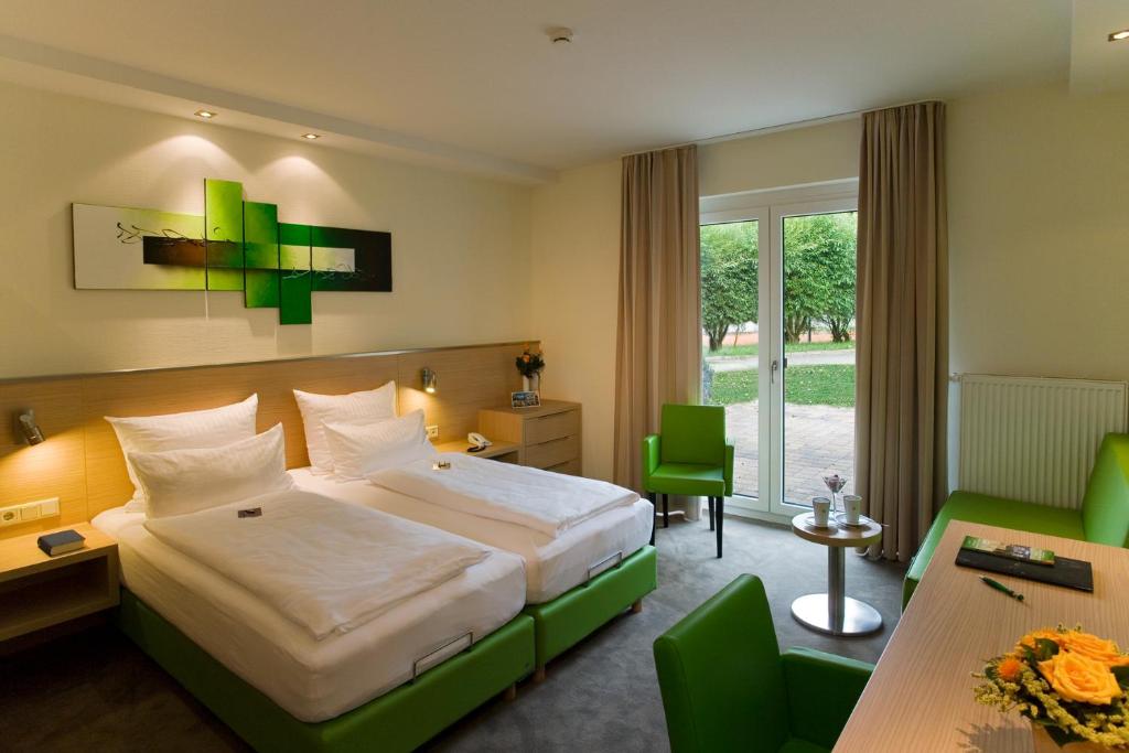 een hotelkamer met een bed en een tafel en stoelen bij aktiv Sporthotel Sächsische Schweiz in Pirna