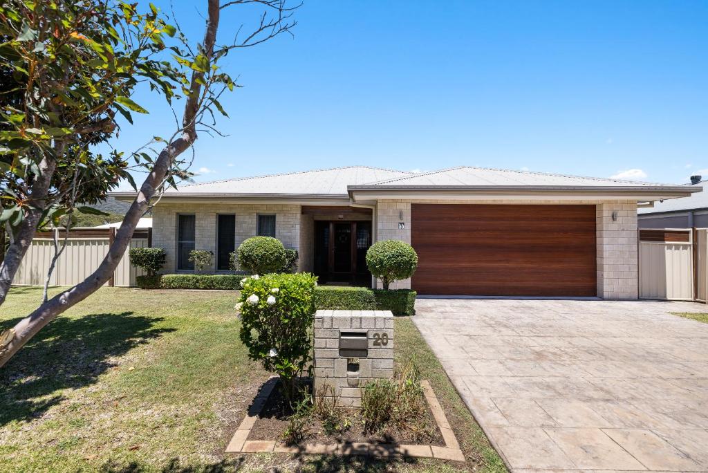 a house with a wooden garage door in a yard at Sea La Vie in Arakoon