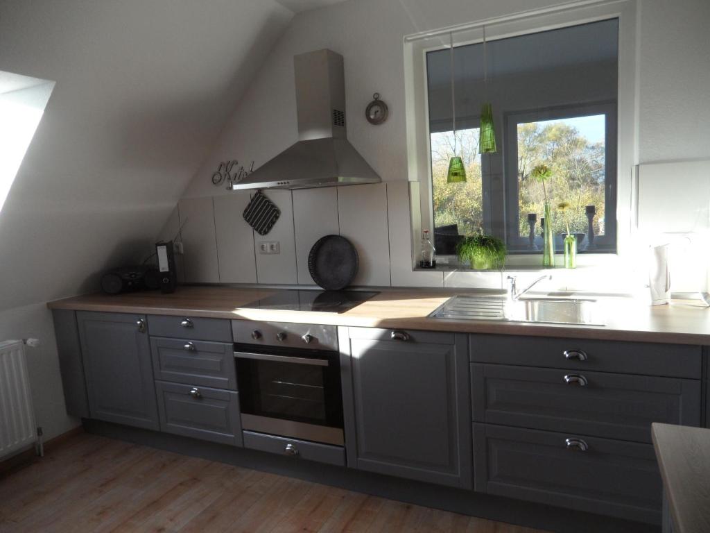 a kitchen with gray cabinets and a sink and a window at Große Wohnung In Diekmannshausen in Süderschweiburg