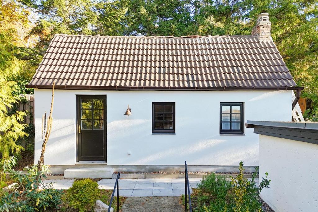 LietzowLandhaus Lietzow Häuschen Tiny Cabin的白色小屋 - 带棕色屋顶