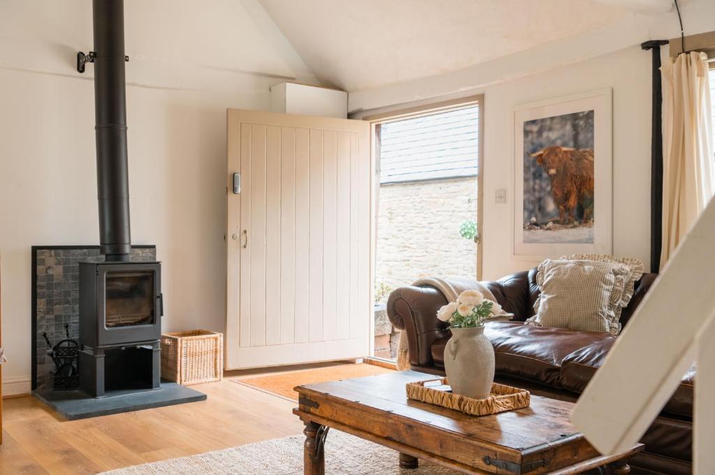 un salon avec un canapé et une cheminée dans l'établissement The Bullpen Cotswolds Farm Stay With Pool, à Lechlade