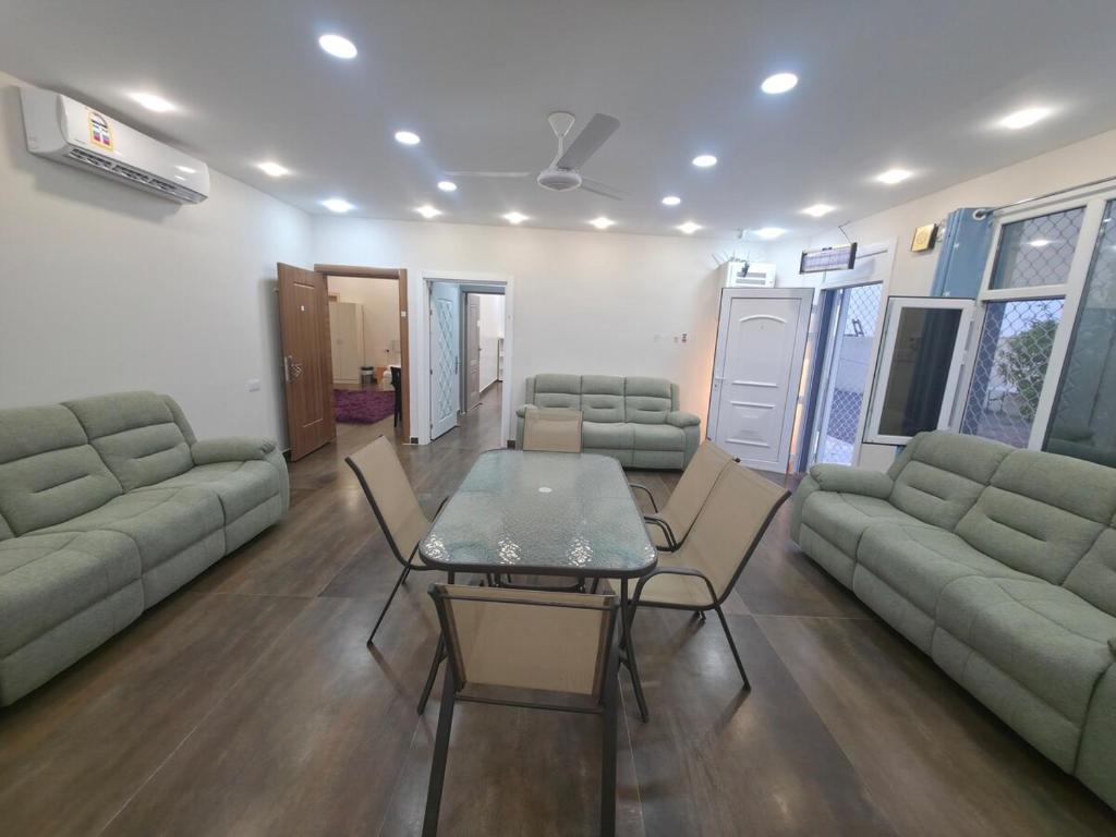ein Wohnzimmer mit einer Couch und einem Tisch und Stühlen in der Unterkunft Chalet - House -Sand Adventures Oasis - Bidiyah - Oman in Jāḩis