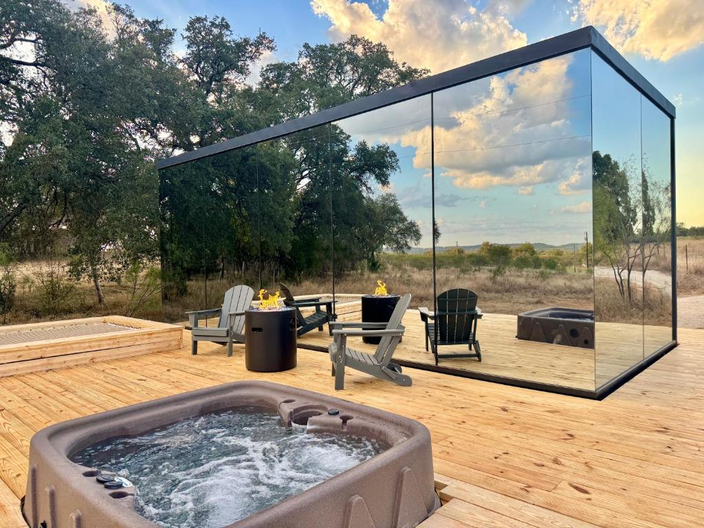 a hot tub on a wooden deck with a glass house at Perseus at The Retreat in Fredericksburg