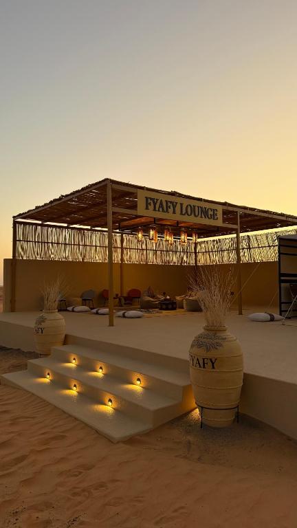 un pabellón con luces en una playa al atardecer en FYAFY Bidiyah Bedouin Camp, en Badīyah