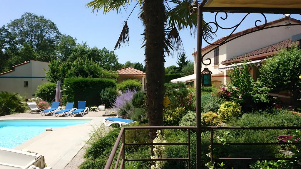 un jardin avec une piscine et une maison dans l'établissement Le Pigeonnier De La Villa Lamoure, à Villaudric