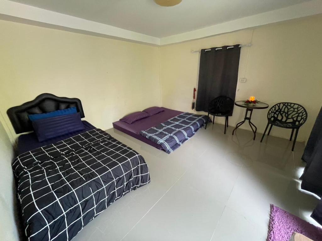a bedroom with two beds and a table and a chair at บ้านมาดาม เขาใหญ่ in Ban Chek