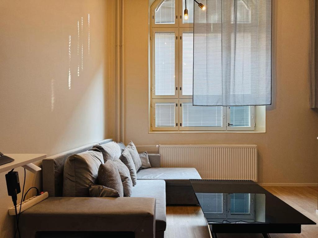 a living room with a couch and a window at Double Sofa Bed in a Stunningly Tall Shared Studio in Helsinki
