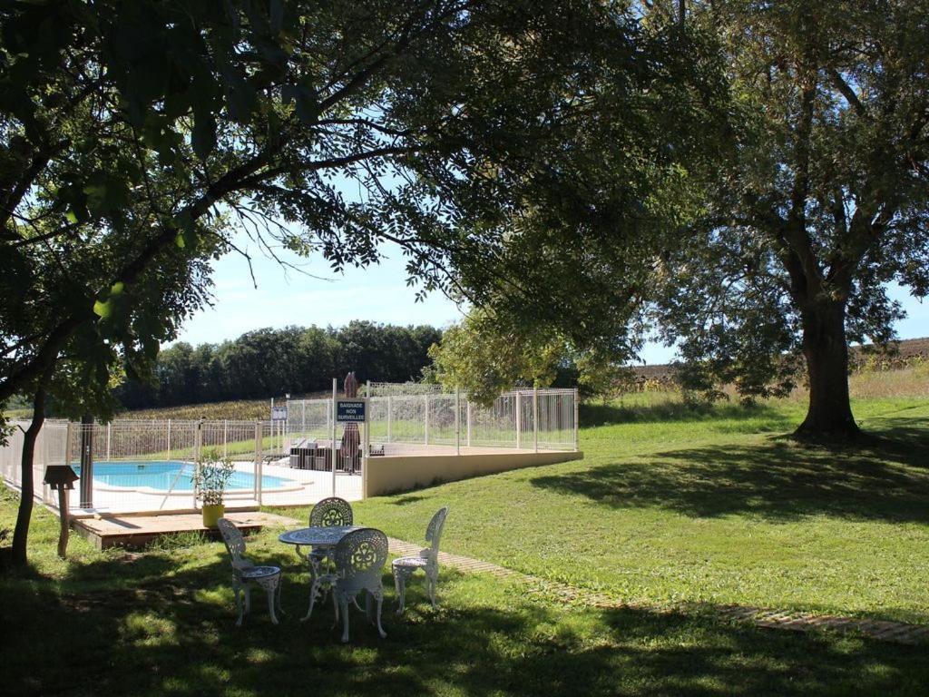 Un parque con mesa y sillas y una piscina. en Gîte de Mandarou, en Castelsagrat