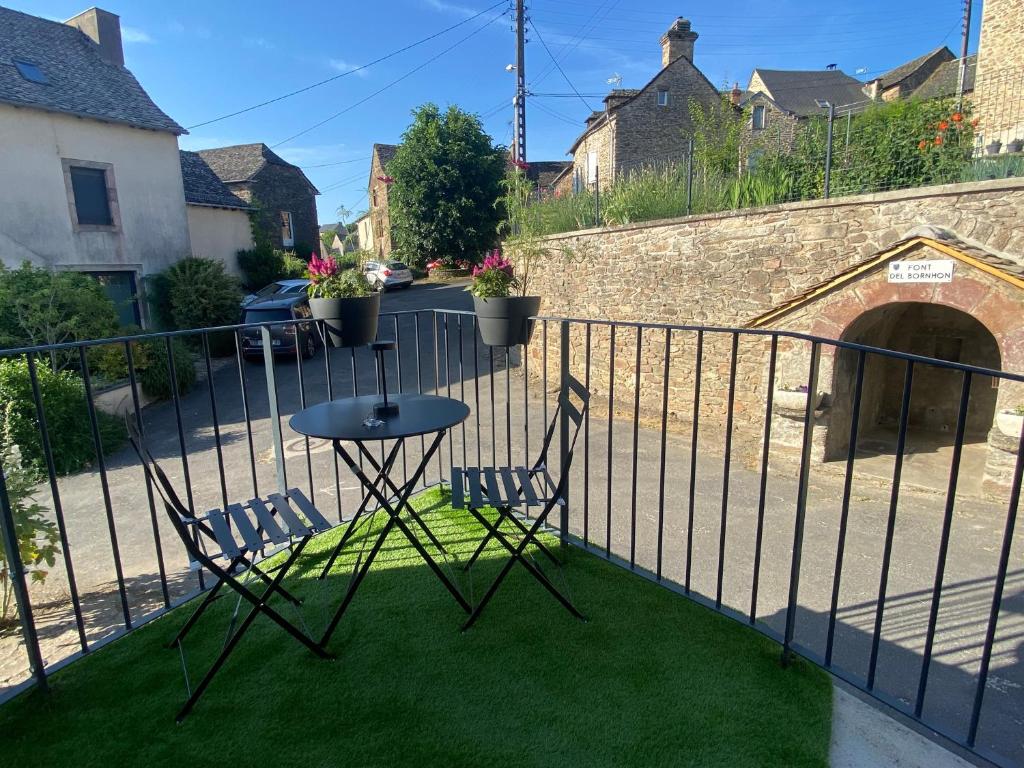 2 stoelen en een tafel op een balkon met gras bij La Petite Maison in Moyrazès