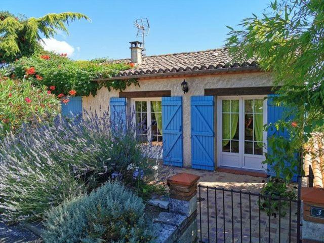 une petite maison avec des portes bleues et une clôture dans l'établissement Gîte de la Fontaine, à Saint-Antoine