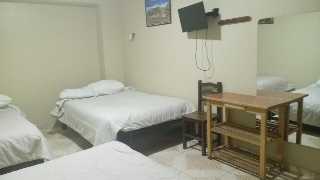una camera con due letti e un tavolo di Hospedaje El Encanto a Huancayo