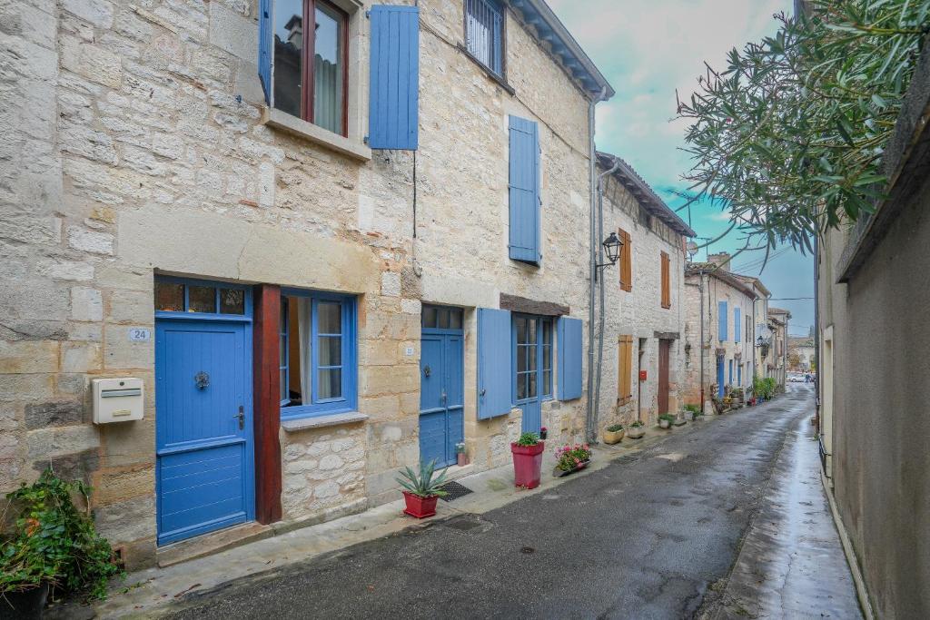 une ruelle avec des portes bleues sur un bâtiment en pierre dans l'établissement La Maison de Julie - Proche Sites Historique, à Septfonds