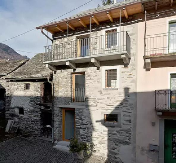 un edificio de piedra con balcón en la parte superior. en Rustico Di Vacanza Nel Nucleo Di Moghegno, en Moghegno