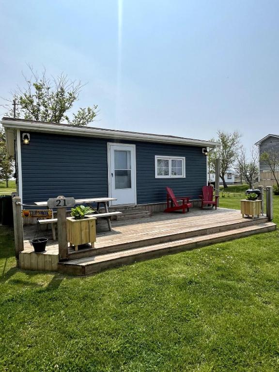 a blue tiny house with a deck and a picnic table at The Nook - Sherbrooke Cottages in Summerside