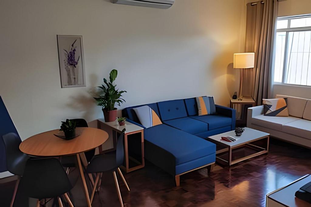 un salon avec un canapé bleu et une table dans l'établissement Casa familiar 2 qts, próx. ao Santuário Nacional, à Aparecida