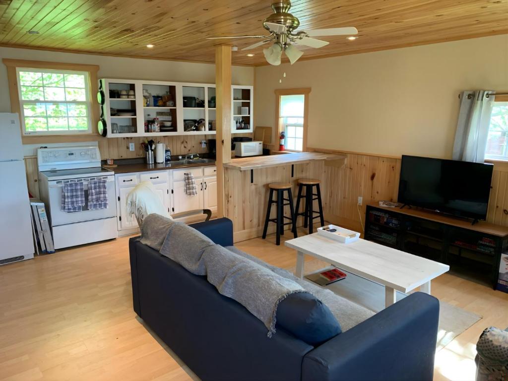un salon avec un canapé bleu et une cuisine dans l'établissement The Nook - Sherbrooke Cottages, à Summerside